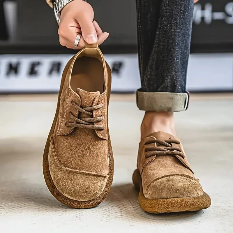 Hellbraune Schnürschuhe: Ein Schuh wird an der Fersenlasche hochgehalten, der andere steht am Fuß mit aufgekrempelter Jeans. 3