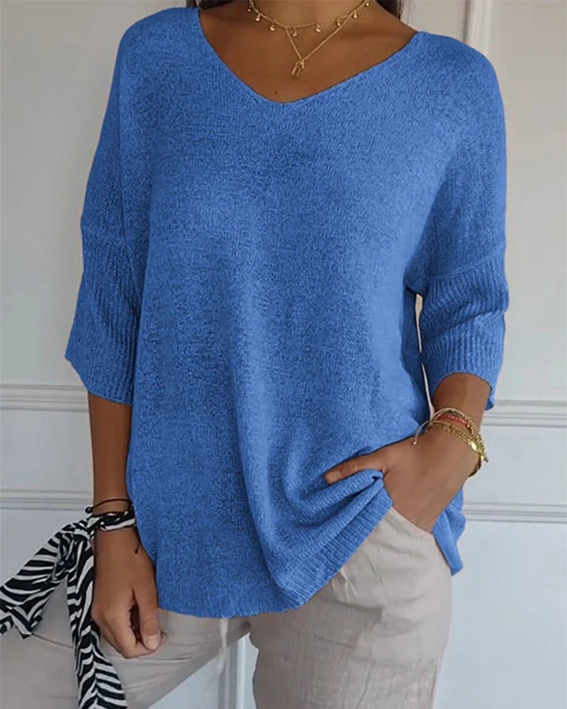 Blauer Strickpullover mit V-Ausschnitt, getragen von einer Frau mit heller Hose, Hand in der Tasche 1
