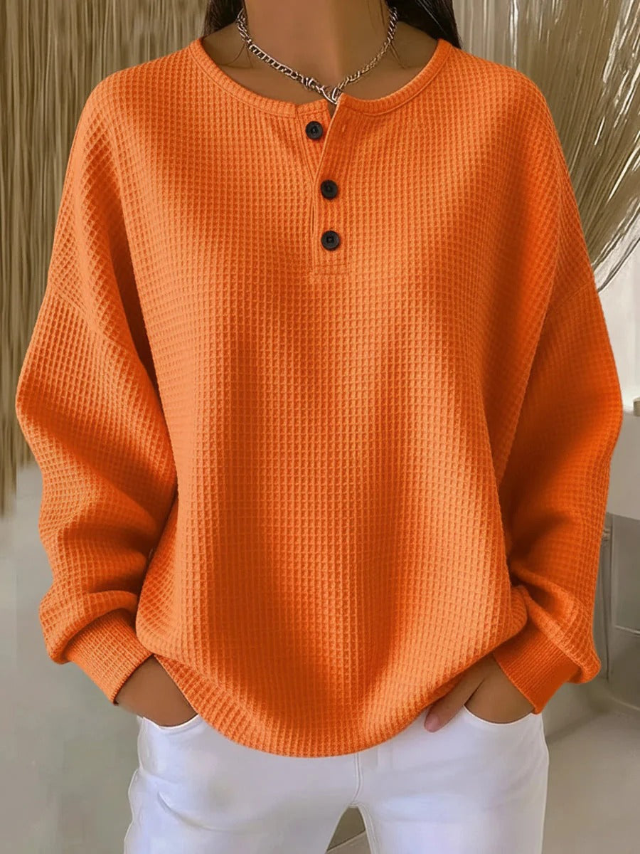 Einfarbig oranger Waffelstrick-Pullover mit drei dunklen Knöpfen am Ausschnitt, getragen zur weißen Hose. 7