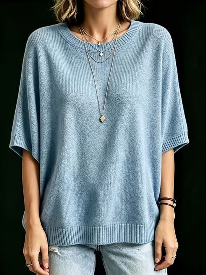 Frontansicht des hellblauen Strickoberteils mit locker fallender Silhouette und gerippten Bündchen, Arme seitlich, dazu helle Jeans. 16