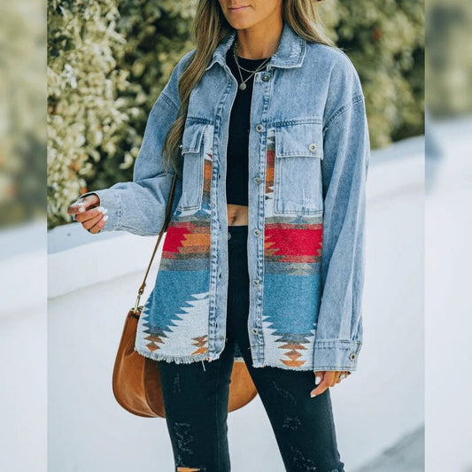 Frau in blauer Jeansjacke mit buntem Aztekenmuster, schwarze Hose, braune Tasche.