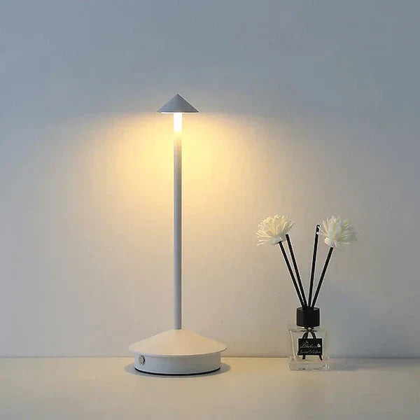 Moderne weiße LED-Tischlampe neben Duftstäbchen in Vase, minimalistisch, energiesparend.