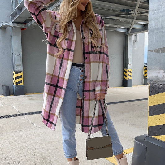 Frau in rosa kariertem Oversize-Hemd, Jeans und Stiefeln, hält eine graue Handtasche.