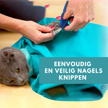 Person schneidet Katzenkrallen mit blauer Schere, Katze in grünem Tuch eingewickelt.