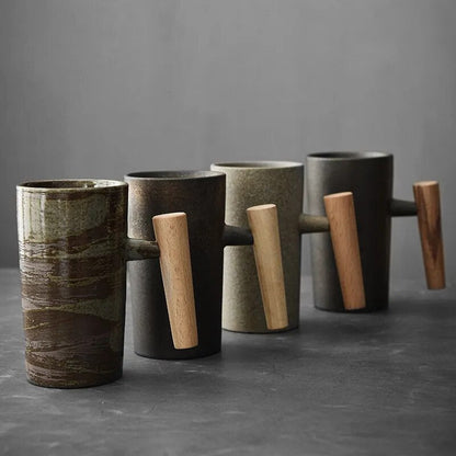 Vier Keramiktassen mit Holzgriffen, modern, minimalistisch, in Erdtönen auf grauem Hintergrund.
