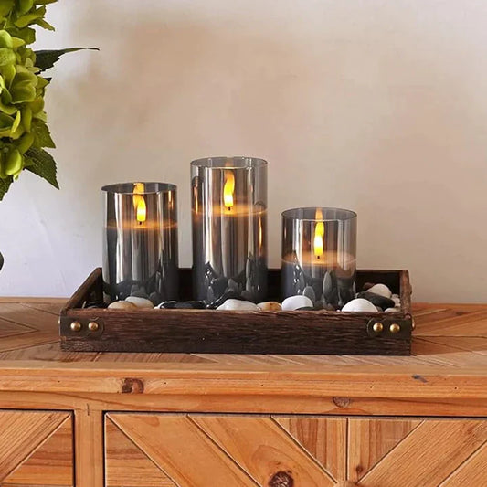 Drei LED-Kerzen in Glaszylindern auf Holztablett, Dekoration, Wohnzimmer, modern, elegant.
