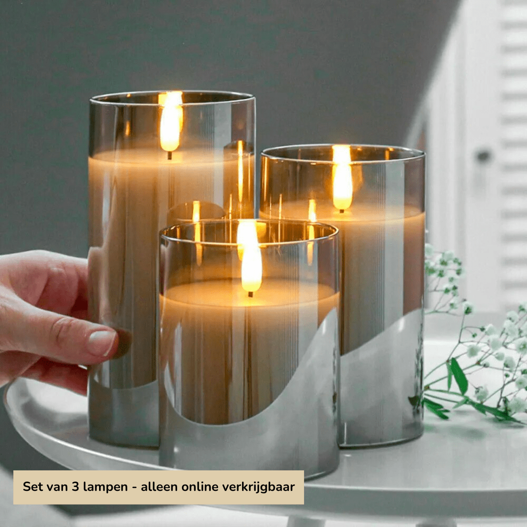 Drei silberne LED-Kerzen, zylindrisch, auf Tablett, moderne Dekoration, warmes Licht.