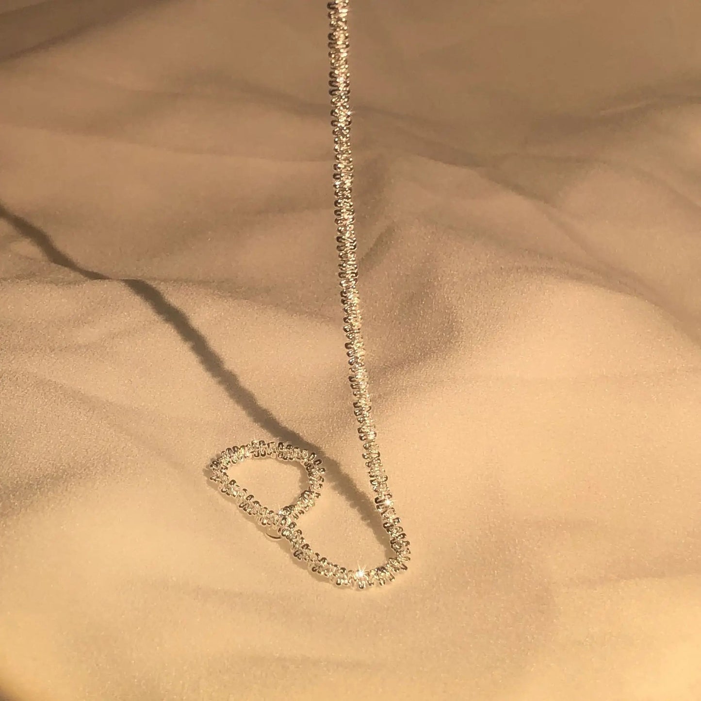 Goldene Halskette mit funkelnden Diamanten auf beigem Stoff, eleganter Schmuck für Damen.