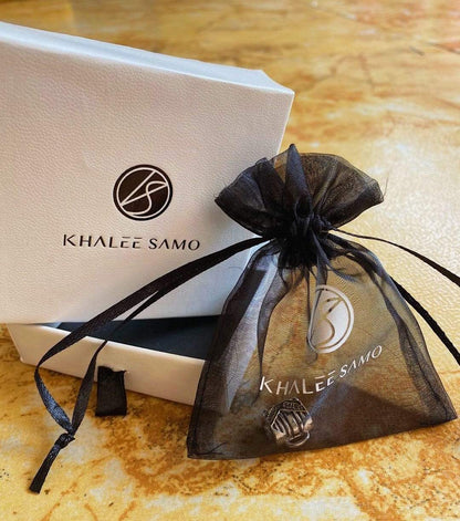 Khalee Samo Opal Herz Halskette in schwarzem Organza-Beutel auf Marmortisch.