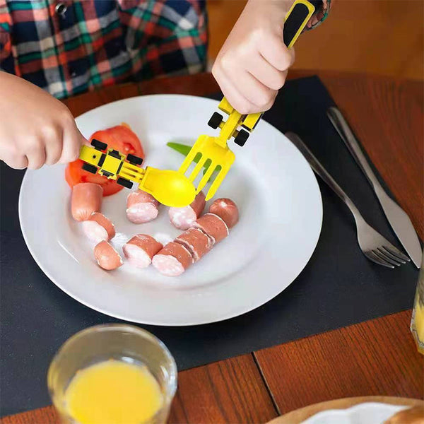 Kinderspielzeug-Besteck in Baggerform, gelb, auf Teller mit Würstchen, Kinderfrühstück.
