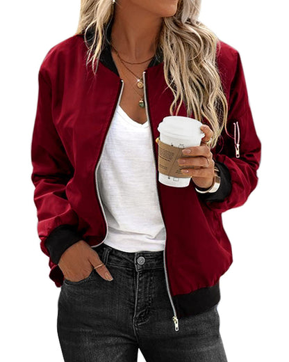 Frau in weinroter Bomberjacke, weißem T-Shirt, hält Kaffeebecher, lässiger Look.