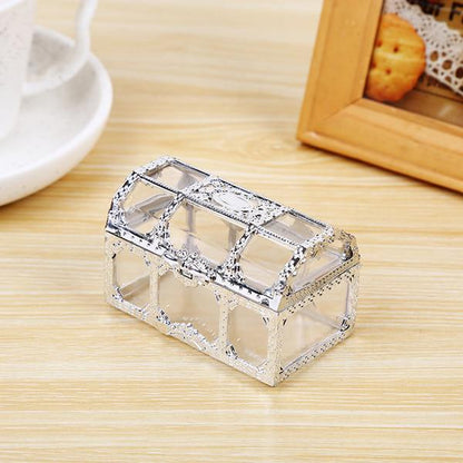 Kleine transparente Schmuckschatulle aus Glas mit silbernem Rahmen auf Holztisch.