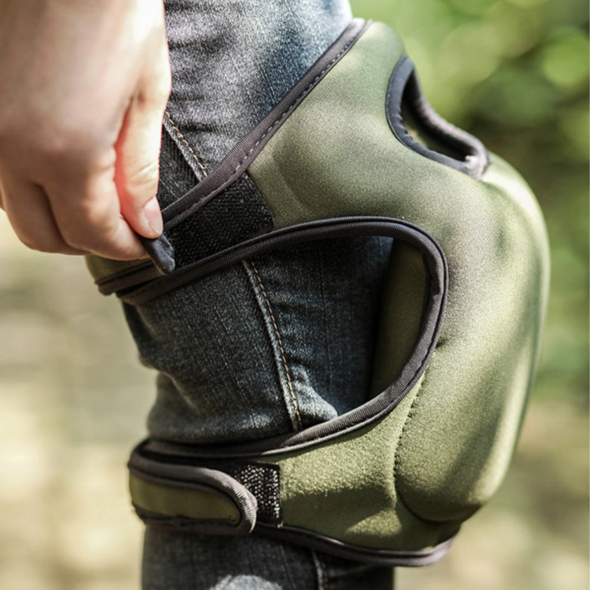 Grüne Knieschoner aus Neopren, verstellbar, für Outdoor-Aktivitäten, auf Jeans getragen.