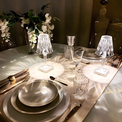 Elegante Tischdekoration mit Kristalllampen, weißen Tellern und Blumenarrangement.