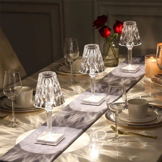 Kristall-Tischlampen auf elegant gedecktem Tisch mit Weingläsern und Rosen im Hintergrund.