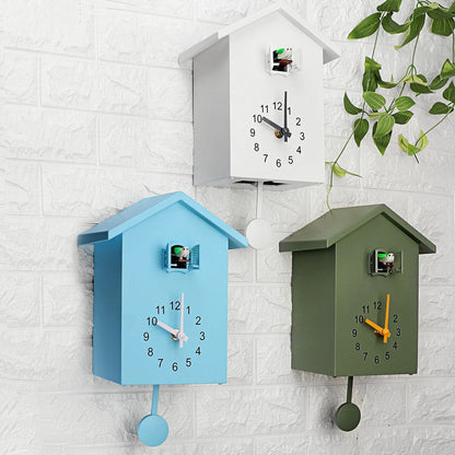 Drei Kuckucksuhren in Blau, Weiß und Grün an Ziegelwand, modernes Design, hängende Pflanzen.
