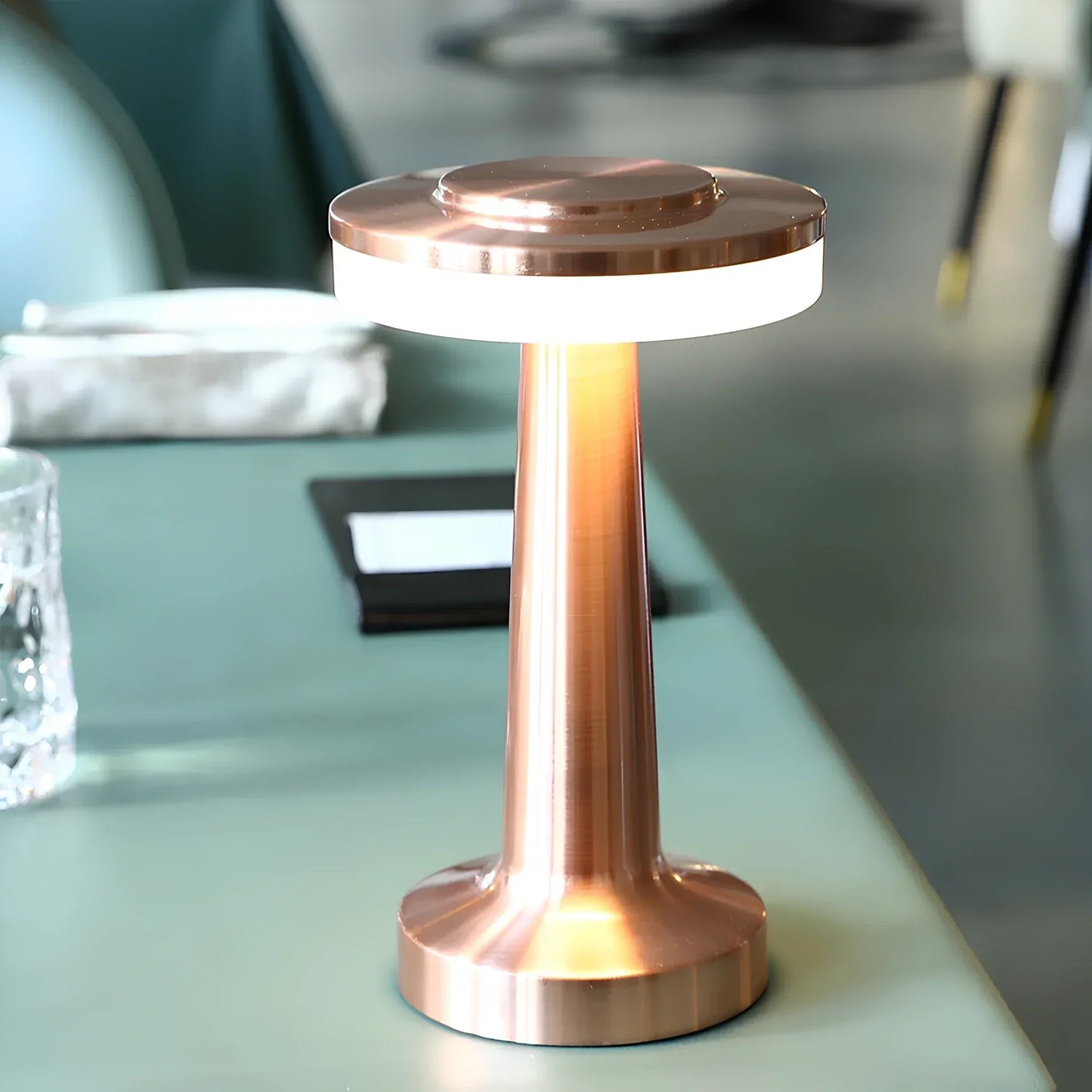 Kupferfarbene LED-Tischlampe auf grünem Tisch, modernes Design, energiesparend, stilvoll.