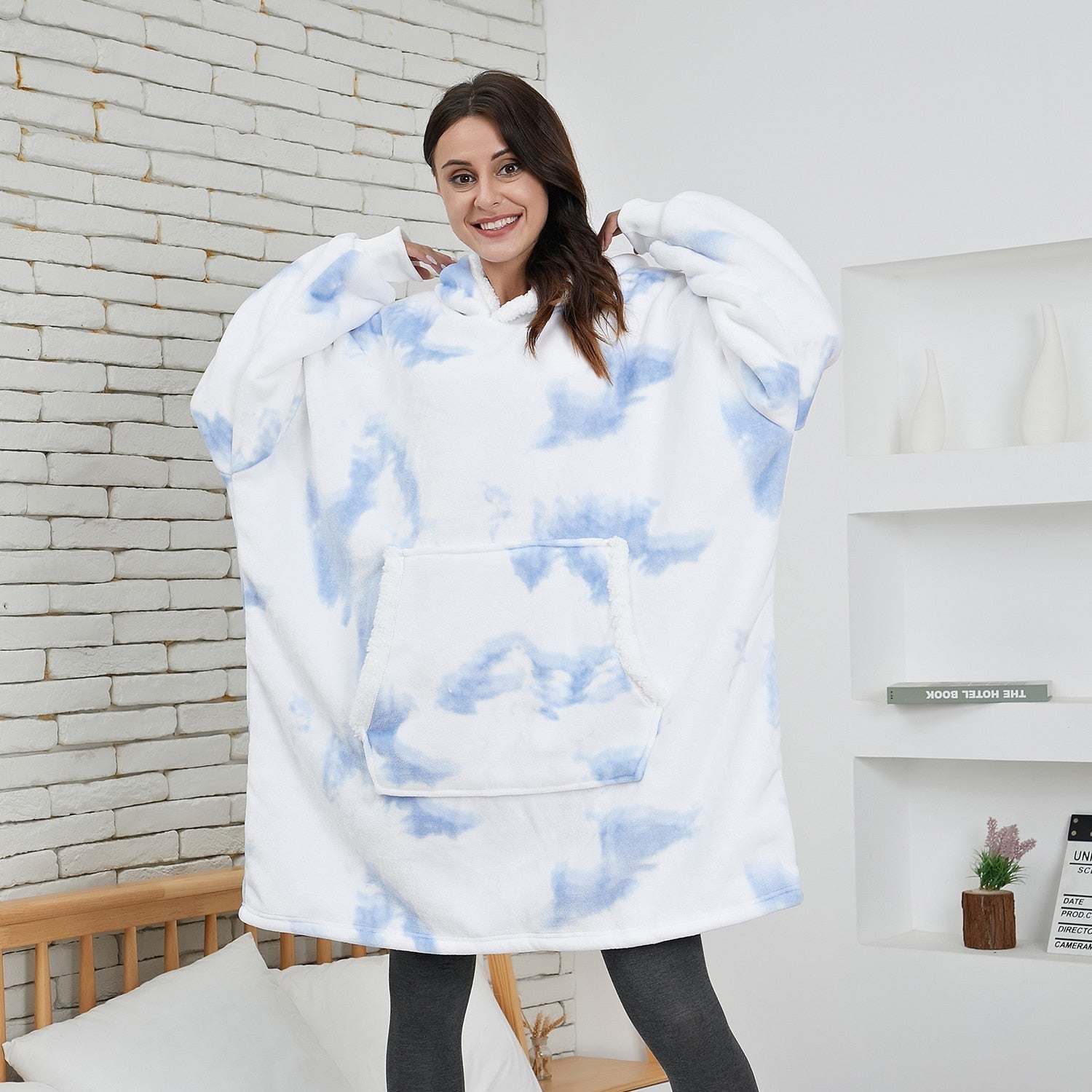 Frau in weiß-blauem Oversize-Hoodie-Decke, gemütlich, Wohnzimmer, lächelnd, Wintermode.
