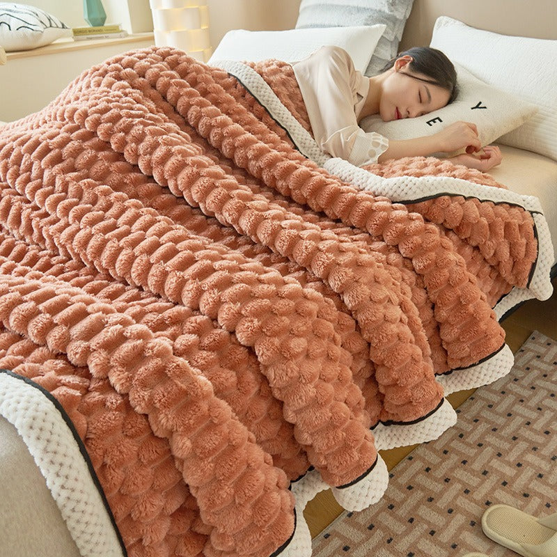 Frau schläft unter einer flauschigen, orangefarbenen Strickdecke im Schlafzimmer.