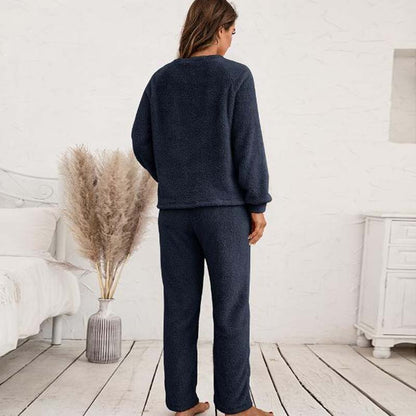 Frau in dunkelblauem Fleece-Pyjama-Set im Schlafzimmer, gemütliche Nachtwäsche.