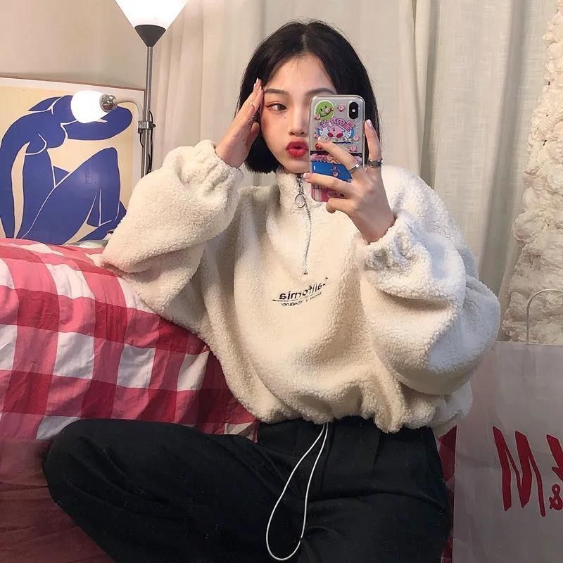 Frau in weißem Fleece-Pullover, Selfie, Handyhülle mit Design, gemütliches Zimmer.