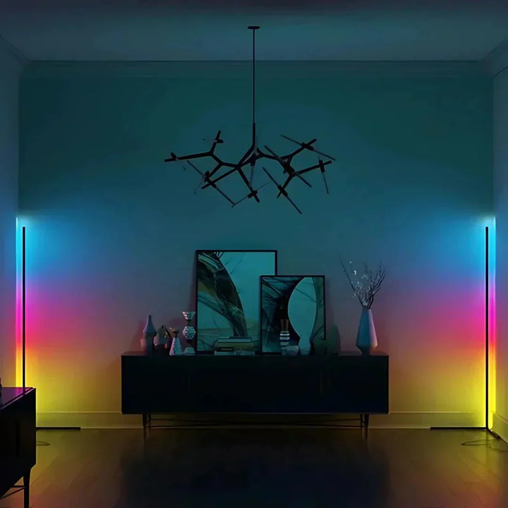 Zwei Eckstehlampen links und rechts im Raum leuchten in Regenbogenfarben von Blau über Pink bis Gelb an der Wand. 4