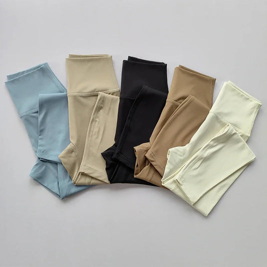 Fünf Paar nahtlose Damenleggings in Blau, Beige, Schwarz, Braun und Creme auf grauem Hintergrund.