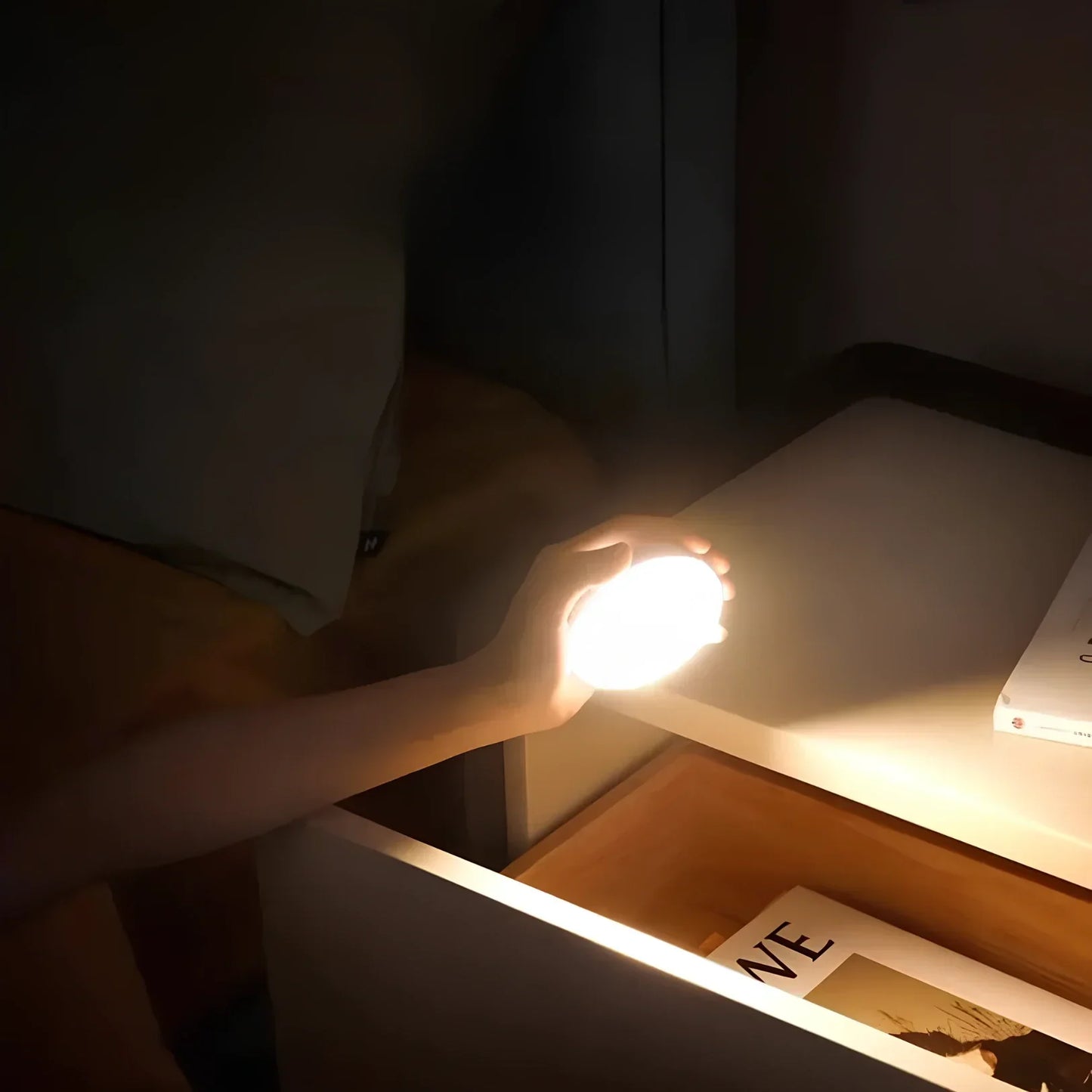 Hand hält leuchtende LED-Lampe am Nachttisch, modernes Design, warmes Licht, Schlafzimmerbeleuchtung.