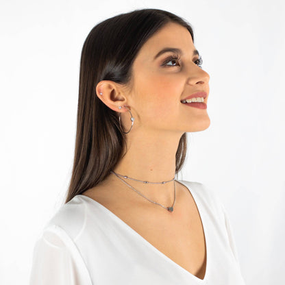 Frau mit silberner Halskette, Ohrringen, weißem Oberteil, Schmuck, Modeaccessoires.