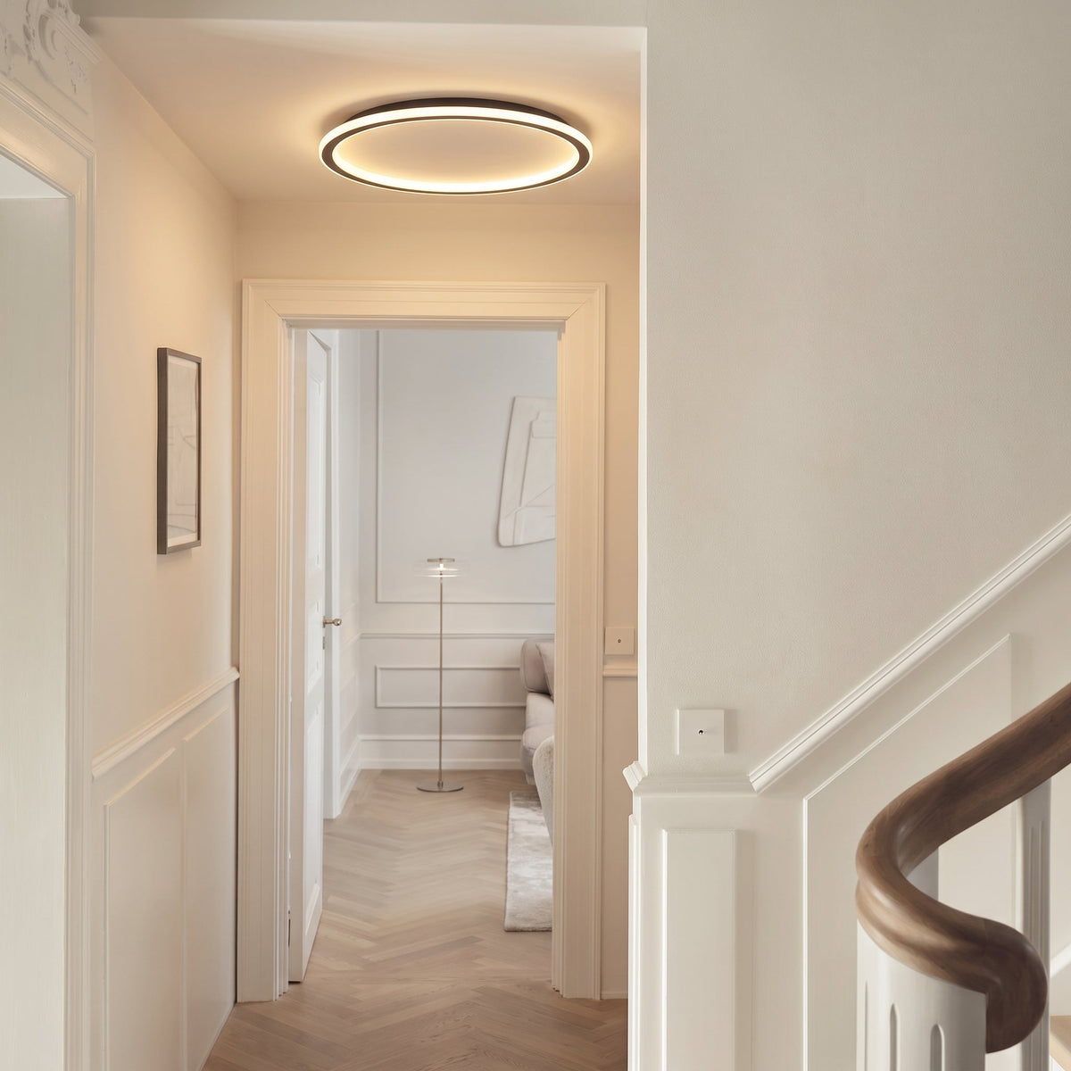 Flache Ringleuchte an der Decke eines hellen Flurs mit Stuckdetails, Fischgrätparkett und Holztreppengeländer. 5