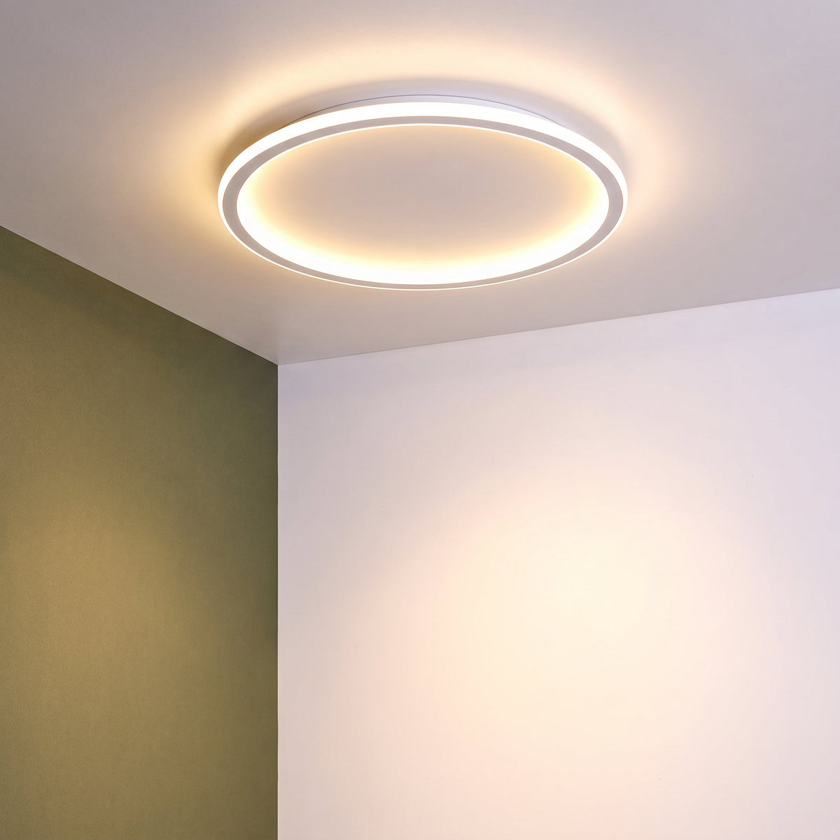 Runde Deckenleuchte in der Raumecke zwischen einer olivgrünen und einer weißen Wand, warm leuchtend. 10