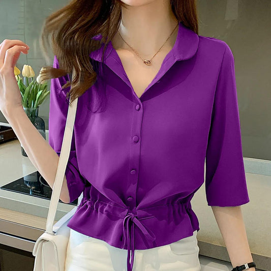 Frau in lila Bluse mit Kordelzug, weiße Hose, moderne Küche, modische Damenbekleidung.