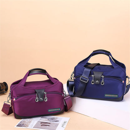 Lila und blaue Nylon-Handtaschen mit Reißverschluss und Schulterriemen auf beigem Hintergrund.