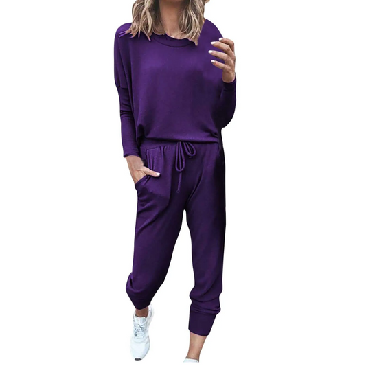 Frau in lila Freizeitanzug, langärmelig, mit Jogginghose, weiße Sneaker.