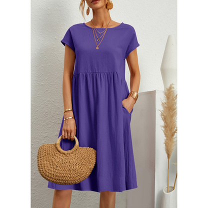 Frau in lila Baumwoll-Leinen-Kleid, A-Linie, mit Strohtasche, Boho-Stil, Sommermode.