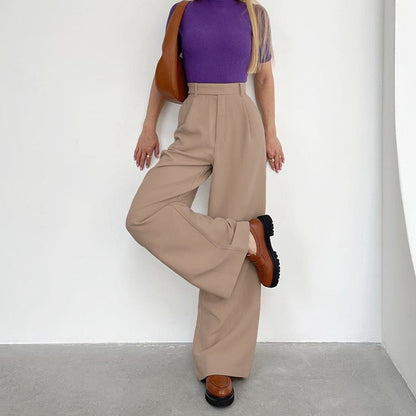 Frau in lila Oberteil und beigen Schlaghosen, braune Schuhe, modisch, elegant, minimalistisch.