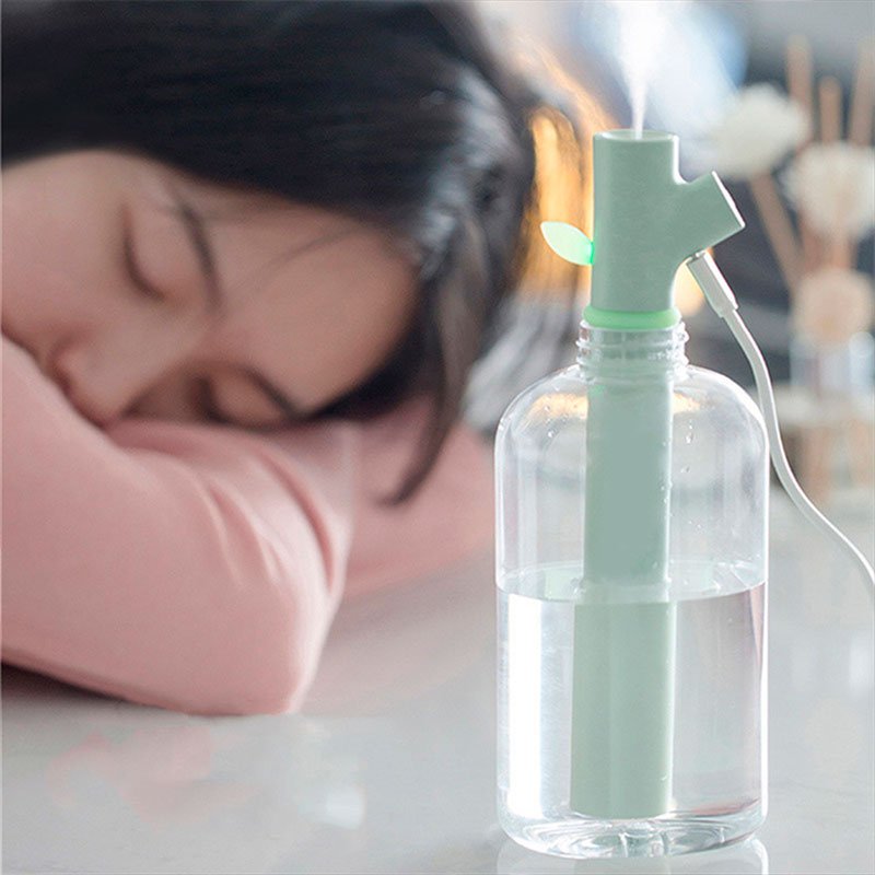 Schlafende Frau neben grünem USB-Luftbefeuchter in Flasche, modernes Design, Raumklima verbessern.