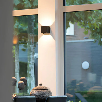 Schwarze Wandleuchte an einer hellen Säule zwischen Fenstern mit Blick in den Garten 7