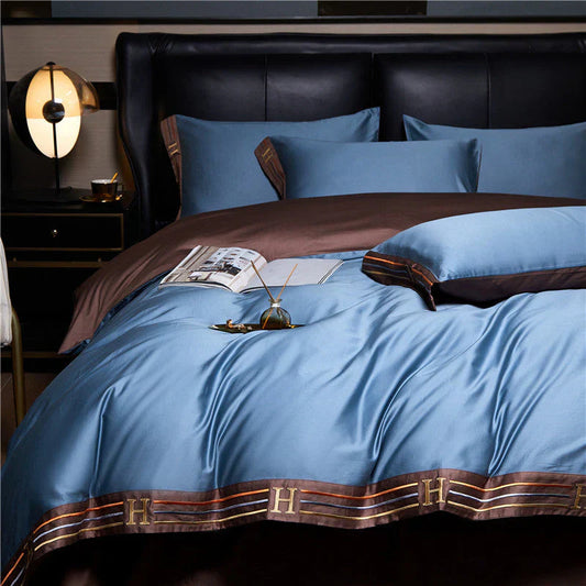 Luxuriöses blaues Bettwäsche-Set aus Seide mit braunen Akzenten und Kissen auf einem Bett.