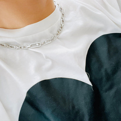 Silberne Halskette mit Kettengliedern auf weißem T-Shirt, luxuriöses Schmuckdesign.