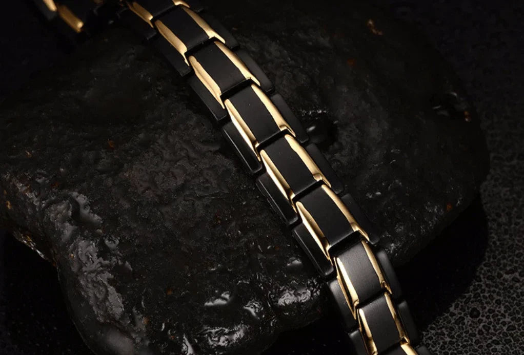 Schwarzes und goldenes Magnetarmband aus Edelstahl auf dunklem Hintergrund.