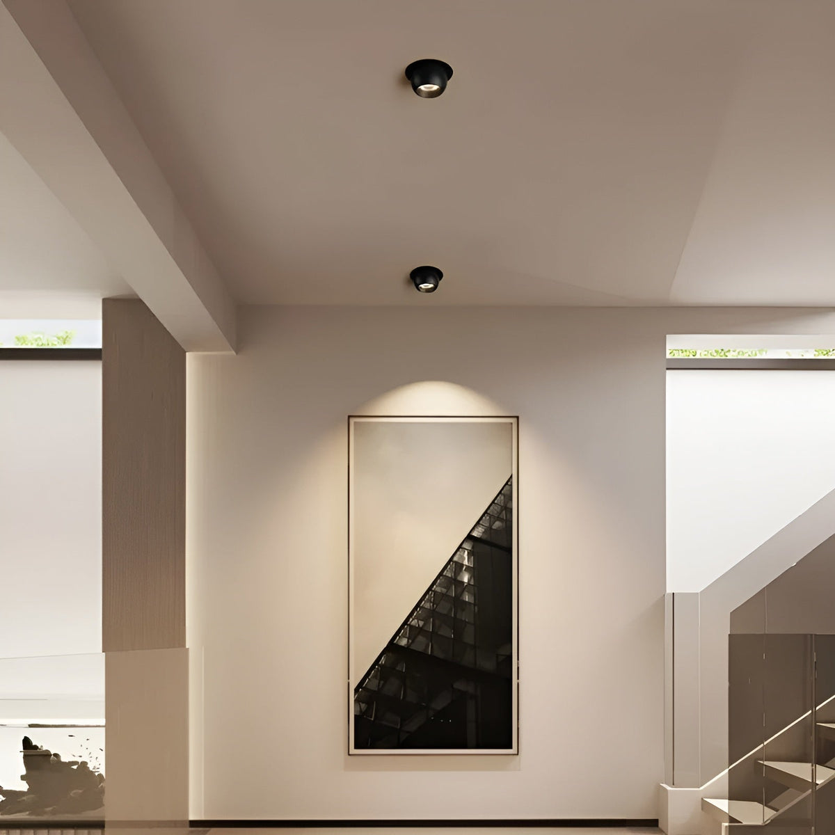Zwei schwarze Einbaustrahler in der Flurdecke setzen ein gerahmtes Wandbild neben der Treppe in warmes Licht 3
