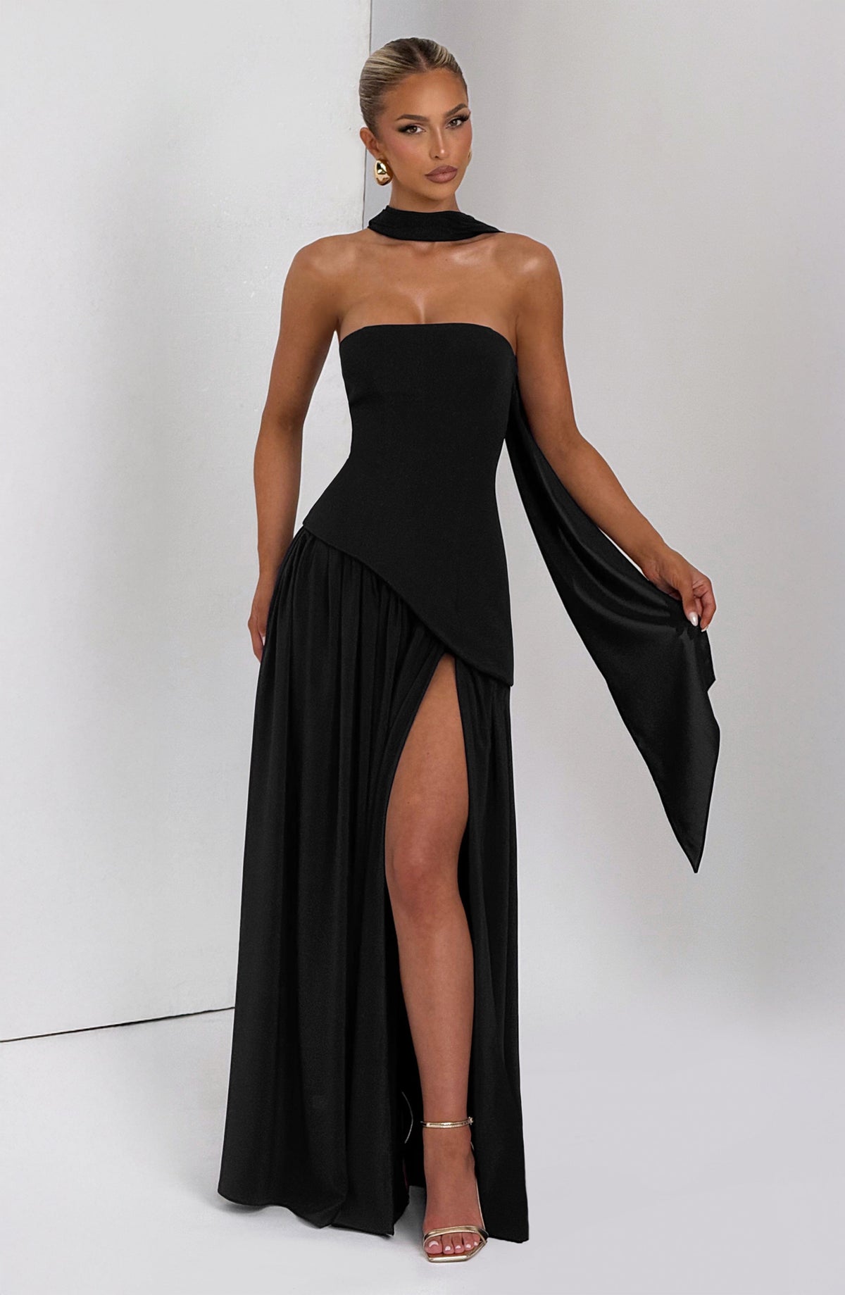 Schwarzes Kleid mit hohem Beinschlitz, Model hält das herabhängende Schalende in der Hand 10