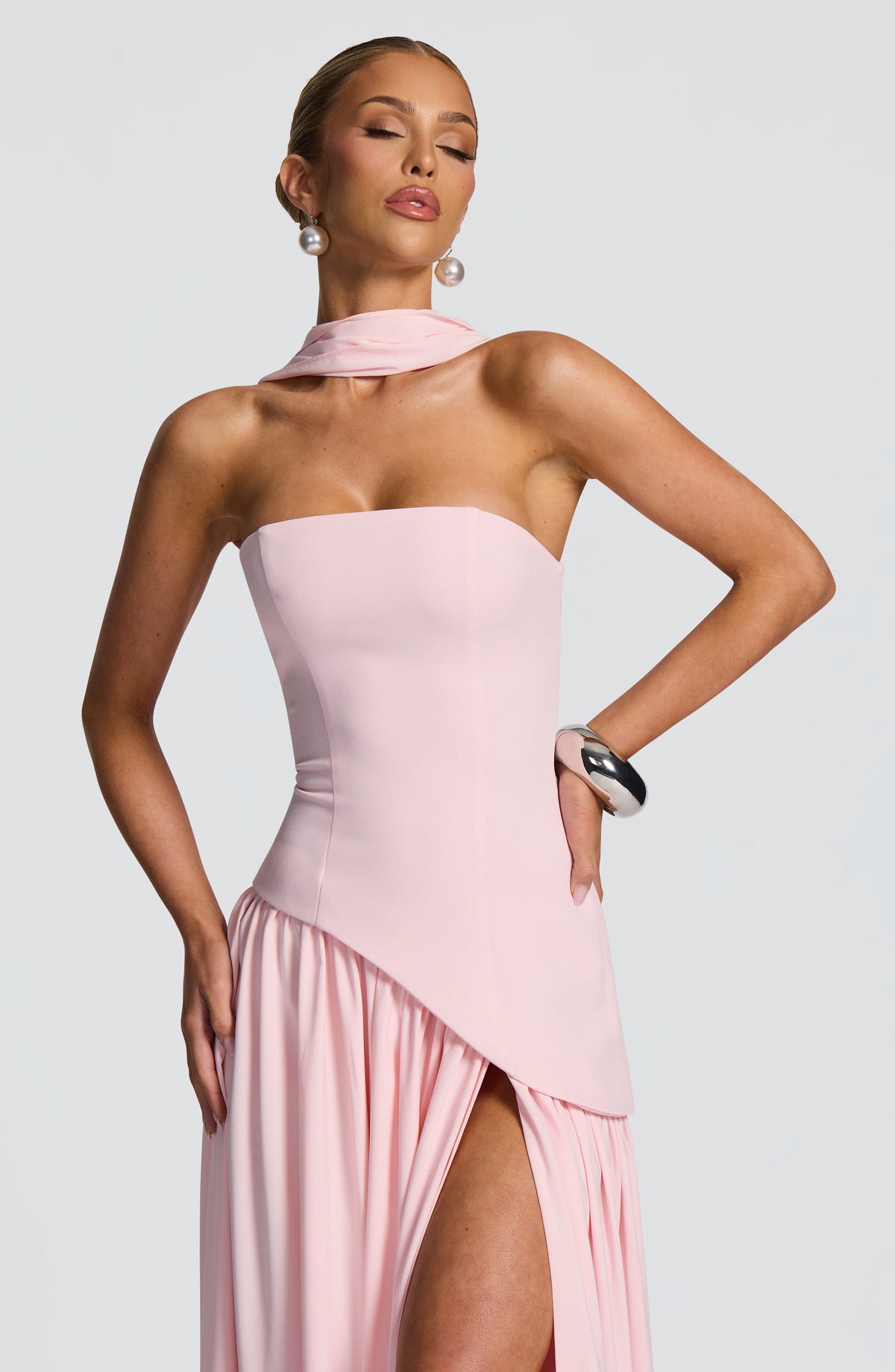 Nahaufnahme des rosa Oberteils mit asymmetrischem Saum, Schalkragen und hohem Rockschlitz, Model mit Hand in der Hüfte 24