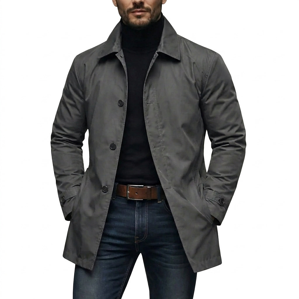Mann trägt den grauen Mantel offen über schwarzem Rollkragenpullover und Jeans, beide Hände in den Taschen, Frontansicht auf weißem Hintergrund. 1