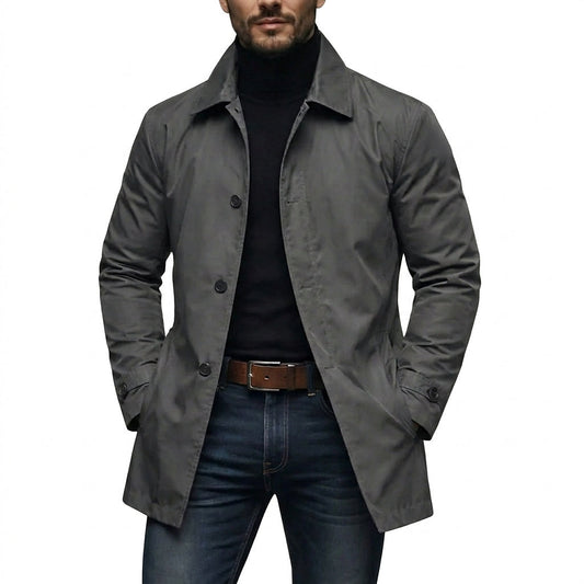 Mann trägt den grauen Mantel offen über schwarzem Rollkragenpullover und Jeans, beide Hände in den Taschen, Frontansicht auf weißem Hintergrund. 1