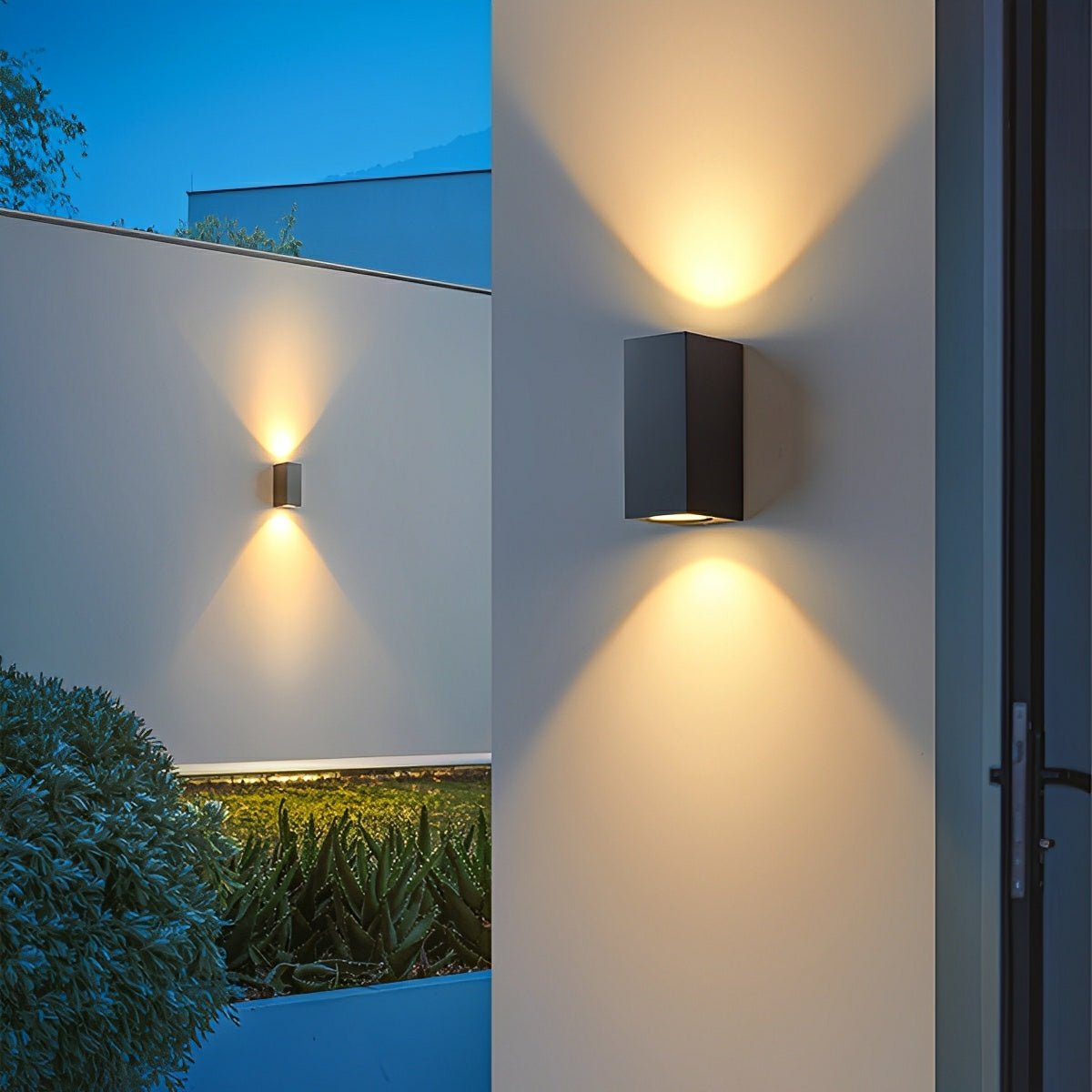 Zwei schwarze Doppellichtleuchten an Hauswänden strahlen Lichtkegel nach oben und unten, Garten im Abendlicht 7