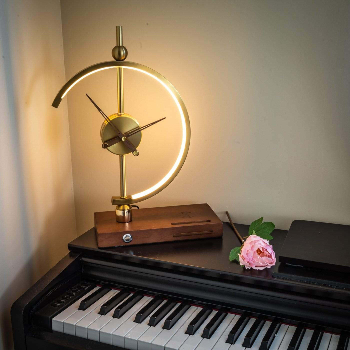 Goldene Tischlampe im modernen Design auf Klavier, mit Holzsockel und dekorativer Blume.