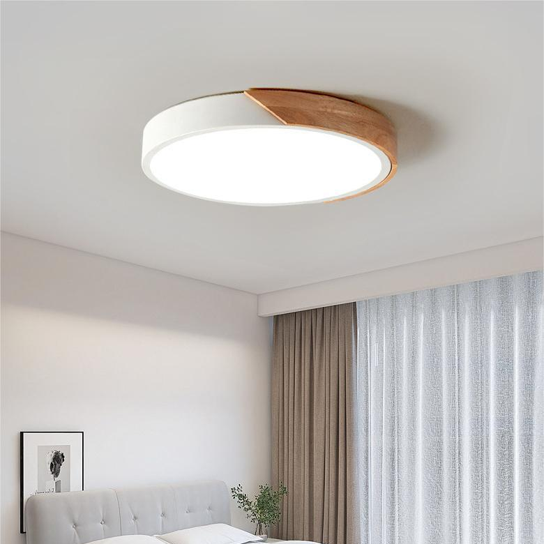 Weiße runde Deckenleuchte mit Holzsegment im Schlafzimmer, neben Vorhängen und einem gepolsterten Bettkopfteil. 3