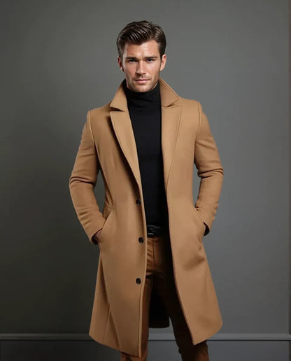 Ganzkörperansicht des kamelbraunen Mantels an einem Model mit Gesicht, Hände in den Taschen, dazu schwarzer Rollkragenpullover und braune Hose. 5